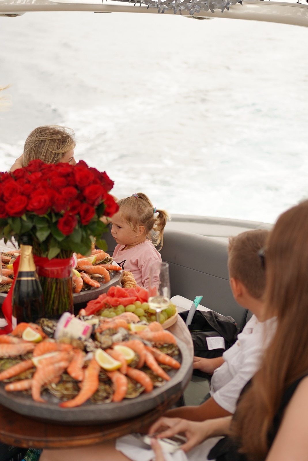 Plateau de fruits de mer et bouquet de roses à bord, en famille